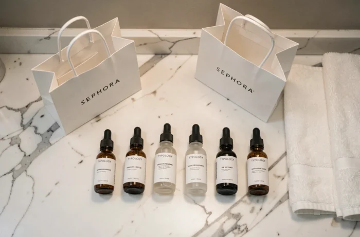 Produits de soin Typology aux emballages minimalistes posés sur un comptoir en marbre avec un sac Sephora
